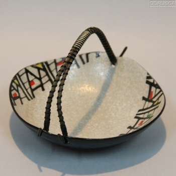 Realizado en cerámica esmaltada con un asa en caña o mimbre con metal plateado y plástico.
